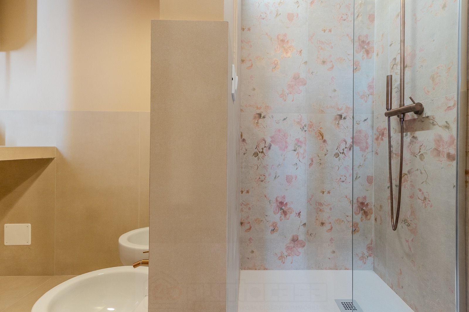 Bagno con doccia walk-in, parete in piastrelle con motivo floreale e toni neutri